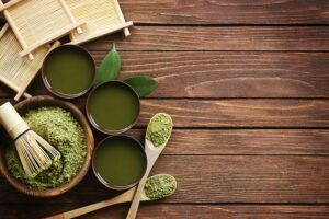 A bowl of matcha tea with a bamboo whisk