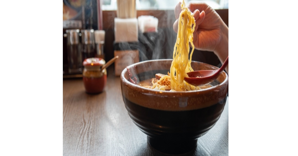 A person happily slurping noodles from a bowl of ramen in Japan, demonstrating the proper ramen etiquette.